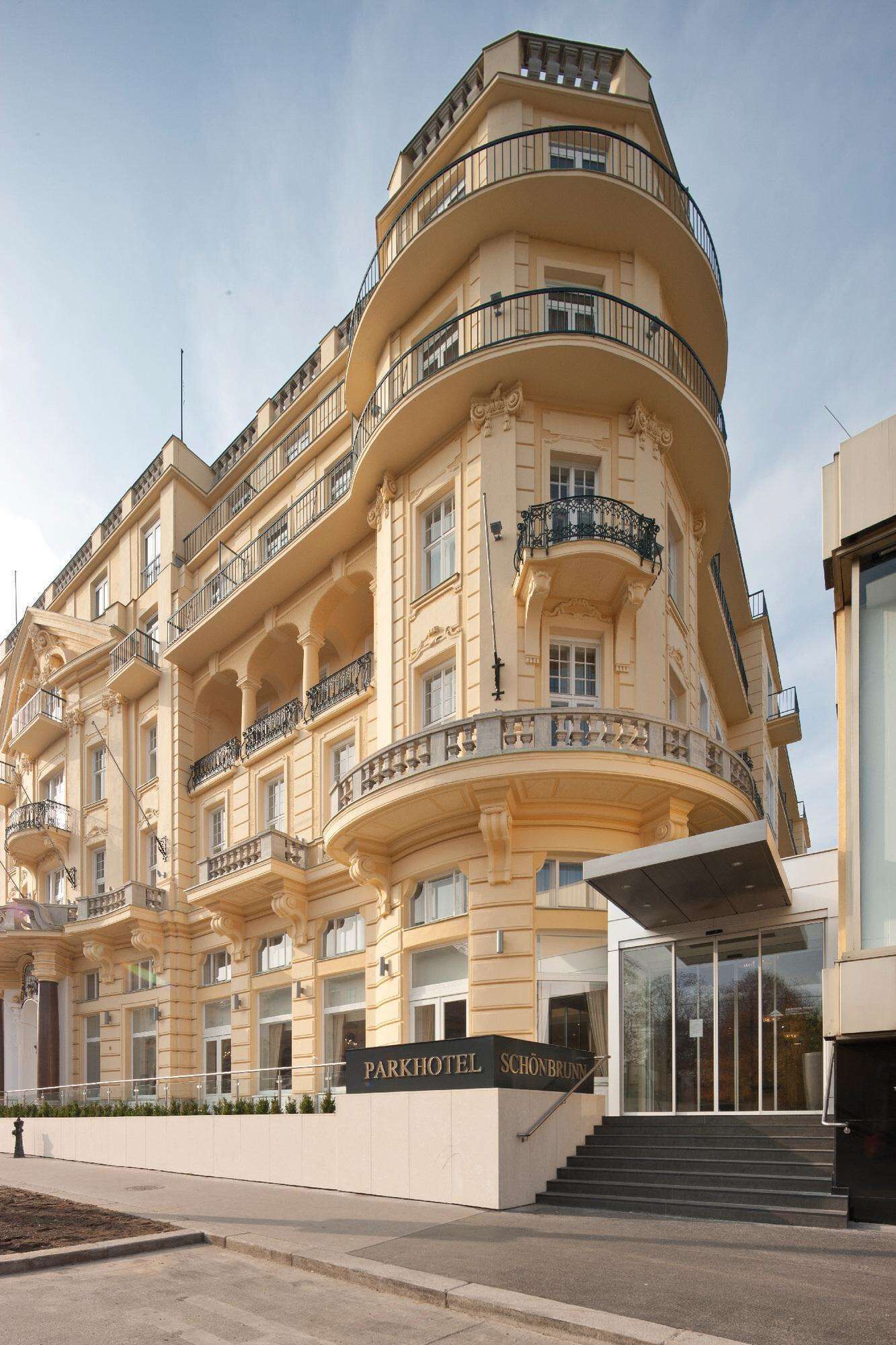Ein mehrstöckiges Hotel mit geschwungener Fassade und Balkonen, mit einem Schild, auf dem 'Parkhotel Schönbrunn' steht.