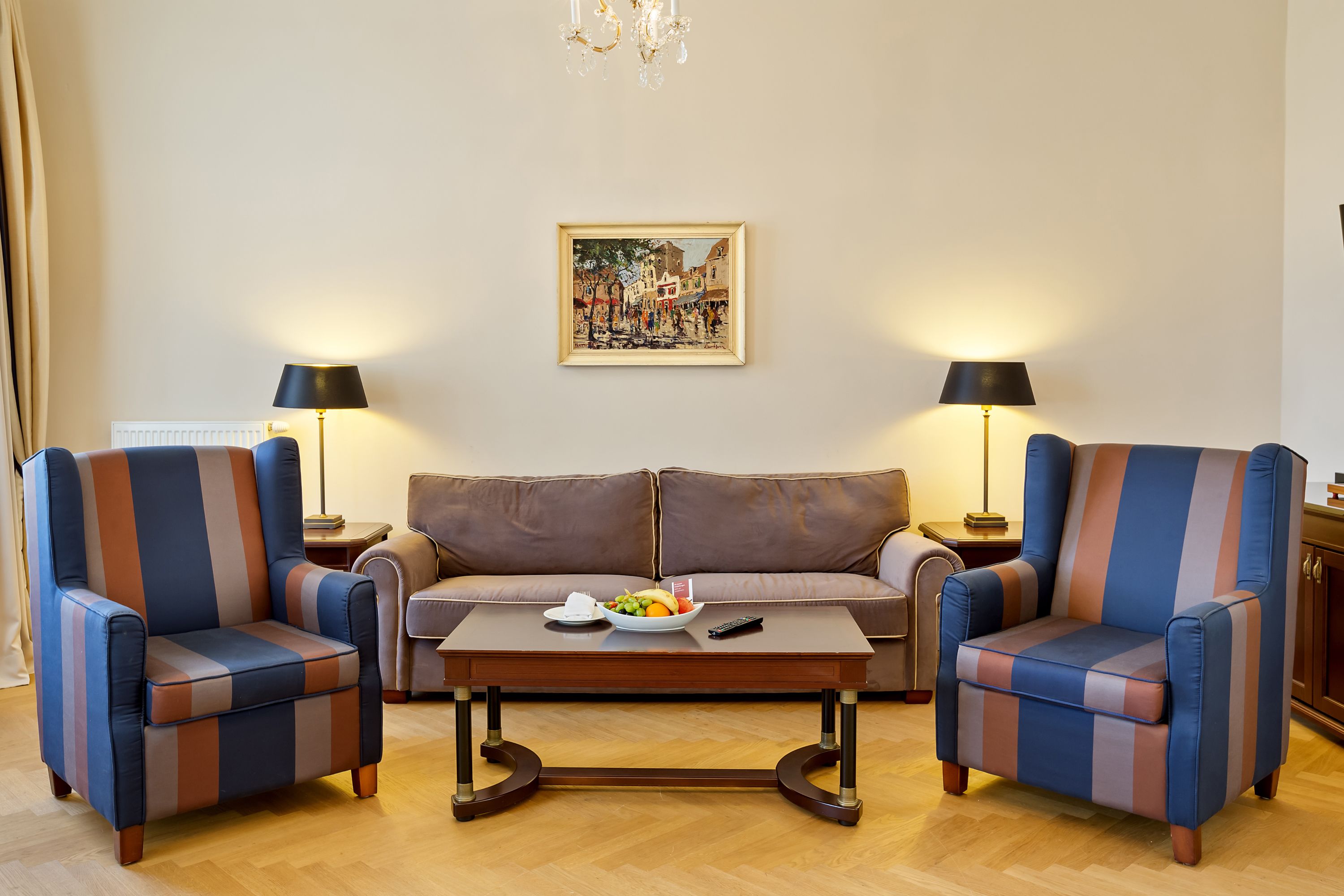 A living room with a sofa, two armchairs, a coffee table, and two lamps.