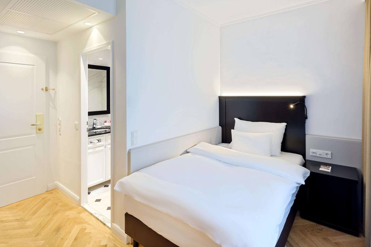 Ein Hotelzimmer mit Bett, Nachttisch und Blick ins Bad.