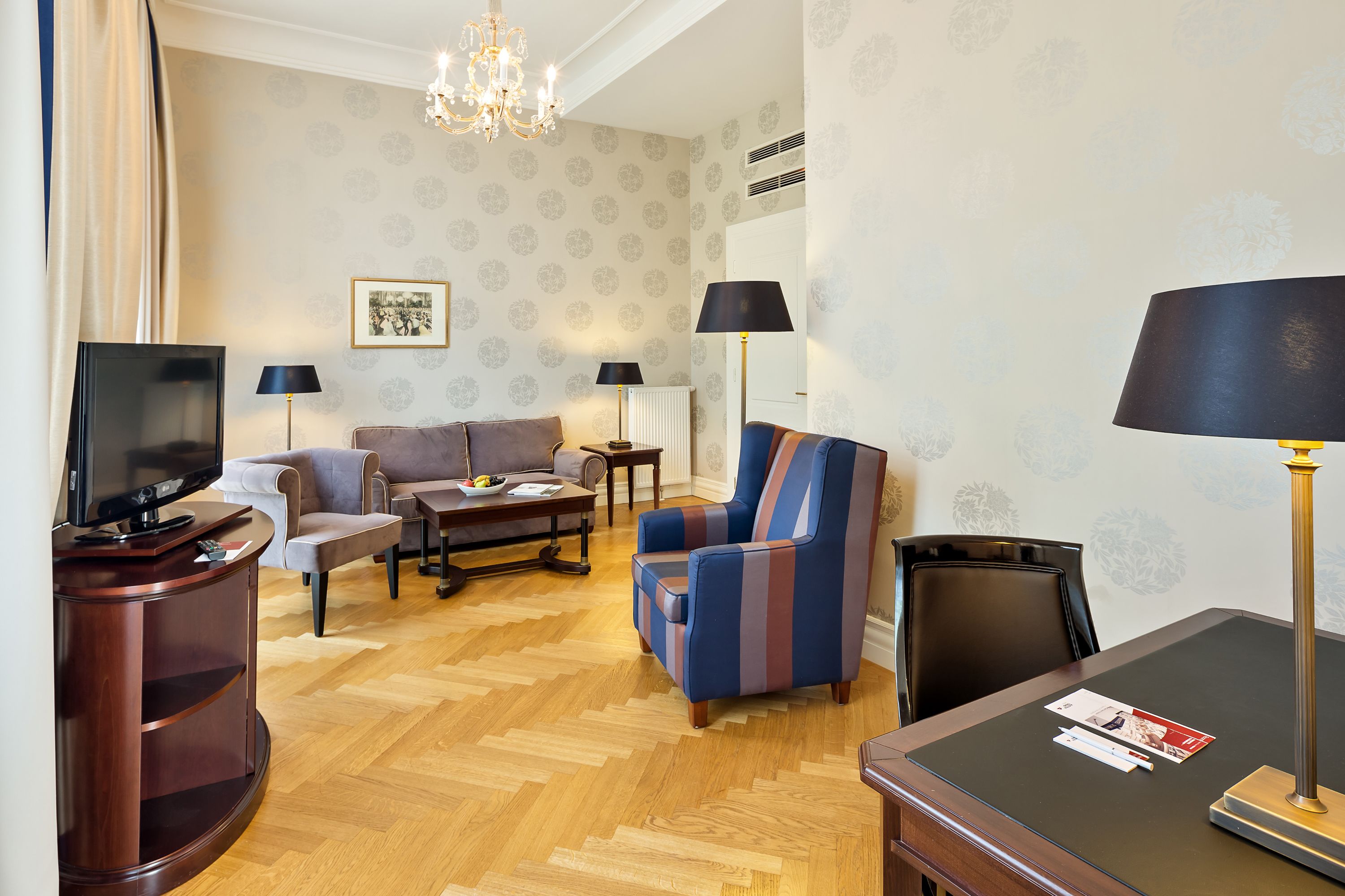 A living room with a TV, sofa, armchair, coffee table, and lamps.
