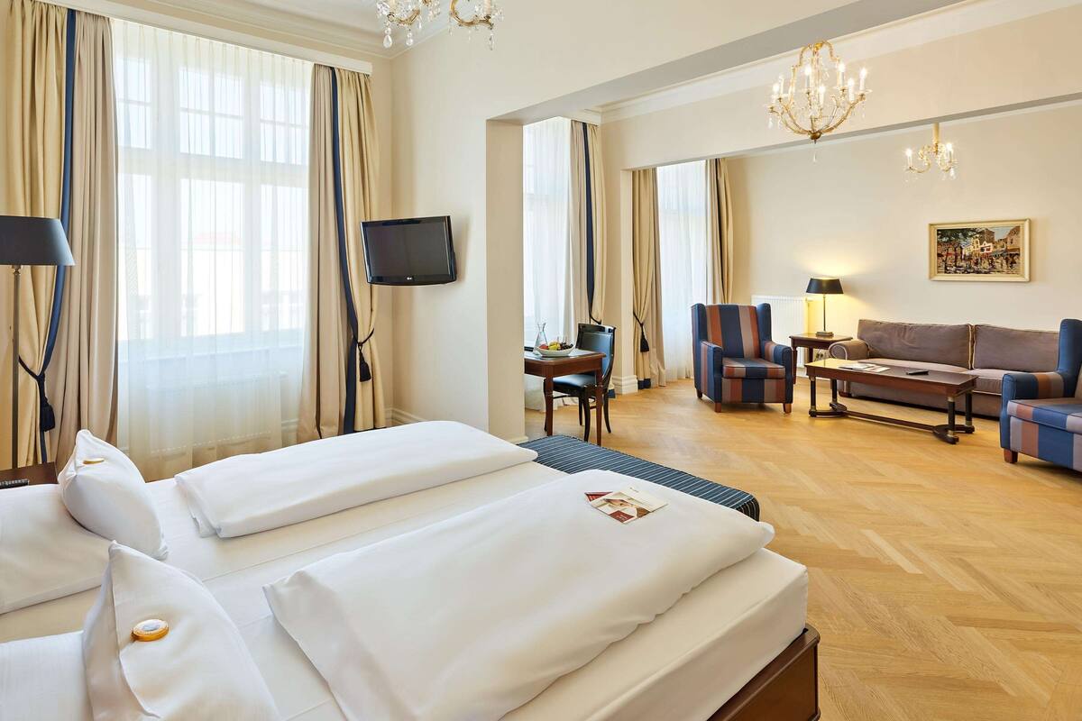 Ein Hotelzimmer mit einem großen Bett, einem Schreibtisch, einem Sessel, einer Couch und einem Fernseher.