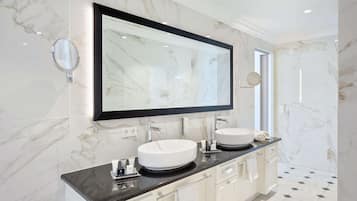 A modern bathroom with two sinks, a large mirror, and marble walls.