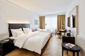 Una habitación de hotel con dos camas, un escritorio, una silla y un televisor.