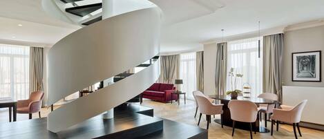 A modern interior with a spiral staircase, a dining area, and a living space with a red sofa and a chandelier.