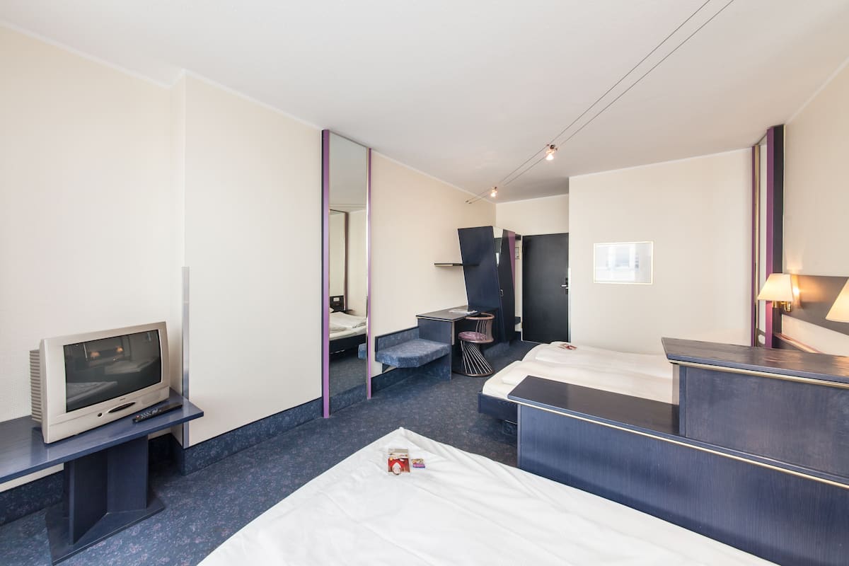 A hotel room with a bed, a desk, a television, and a mirror.