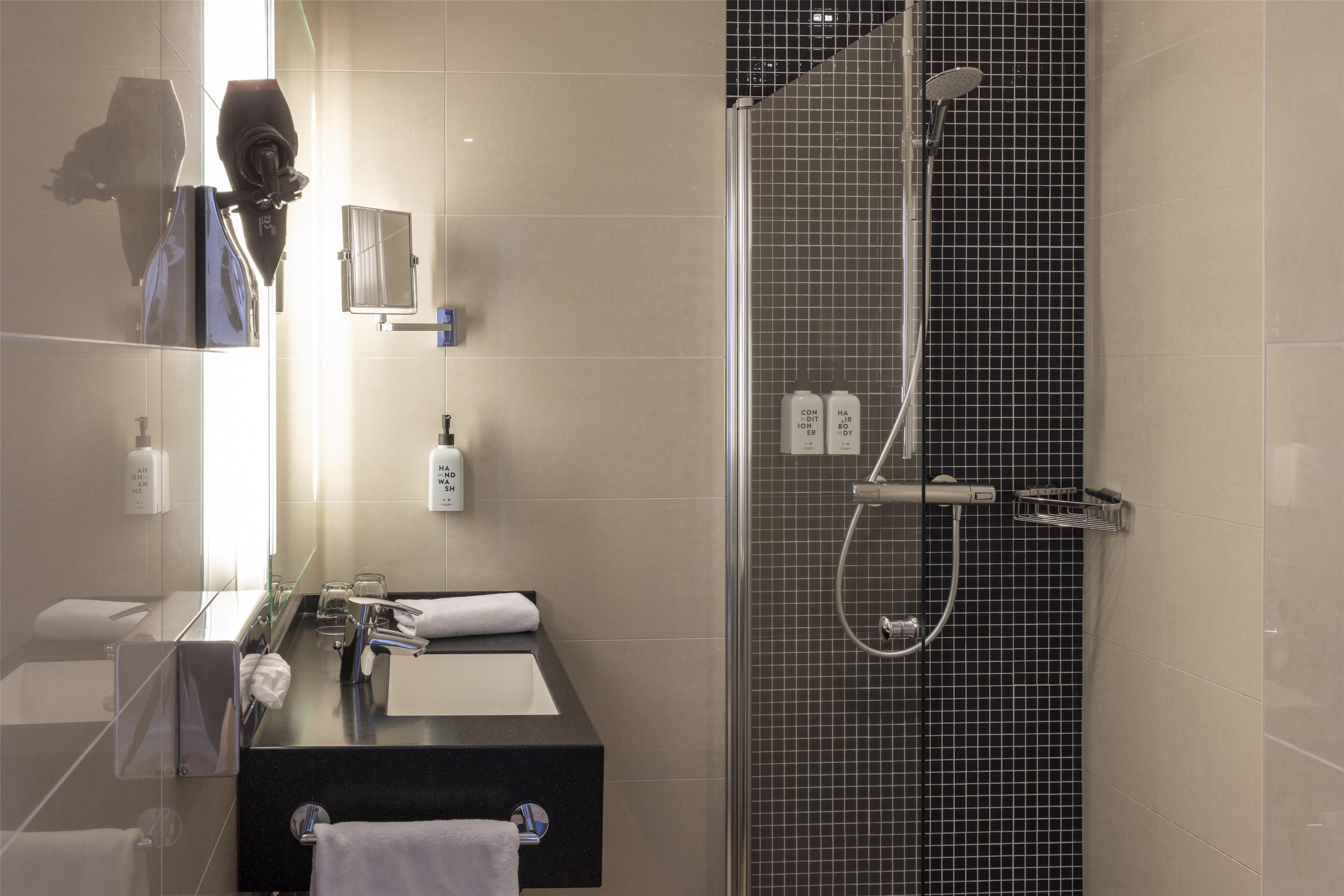 A modern bathroom with a glass shower enclosure, a black countertop sink, and a mirror.