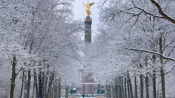 Un sendero cubierto de nieve que conduce a un monumento con una estatua dorada.