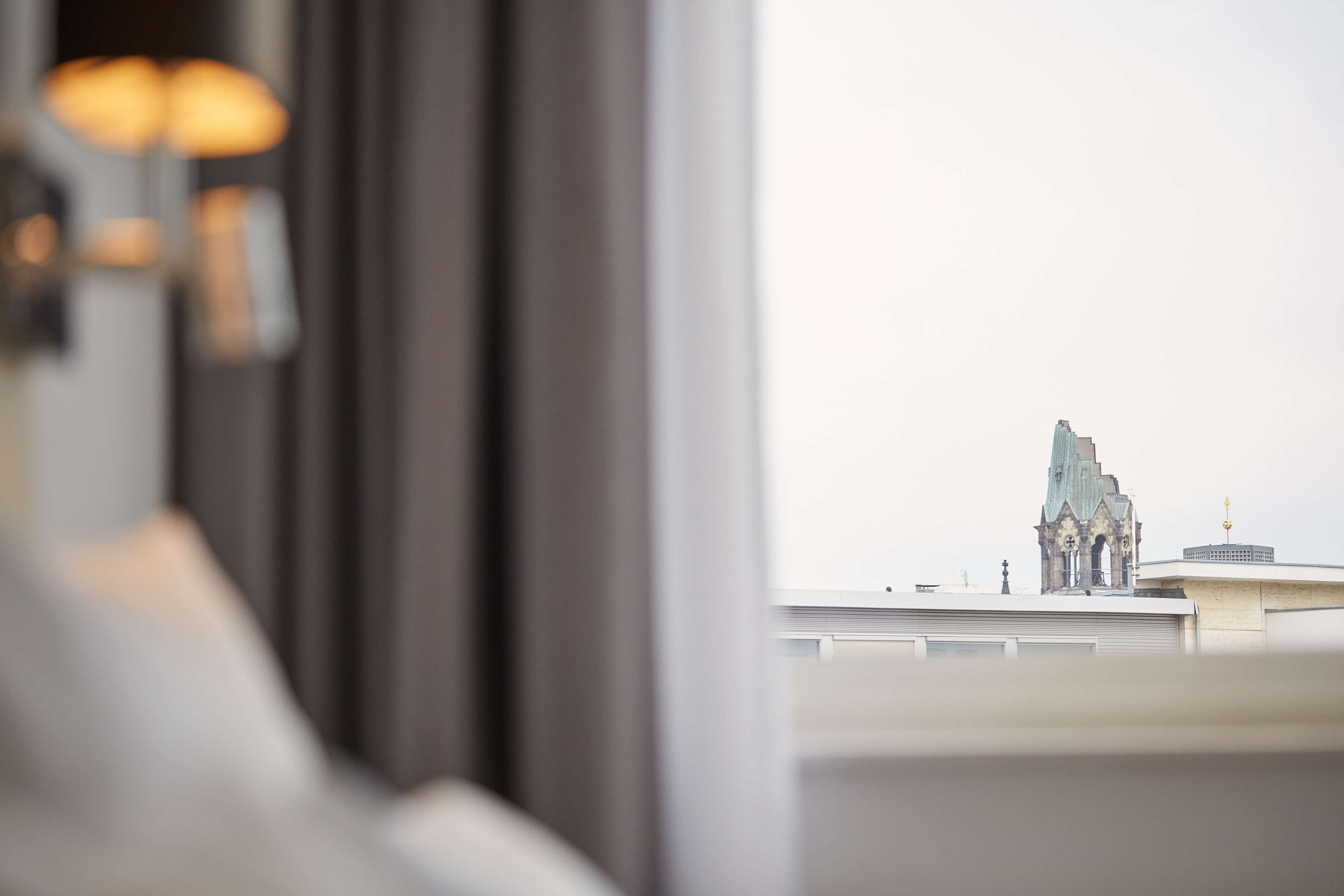 A view from a window overlooking a building with a distinctive tower.