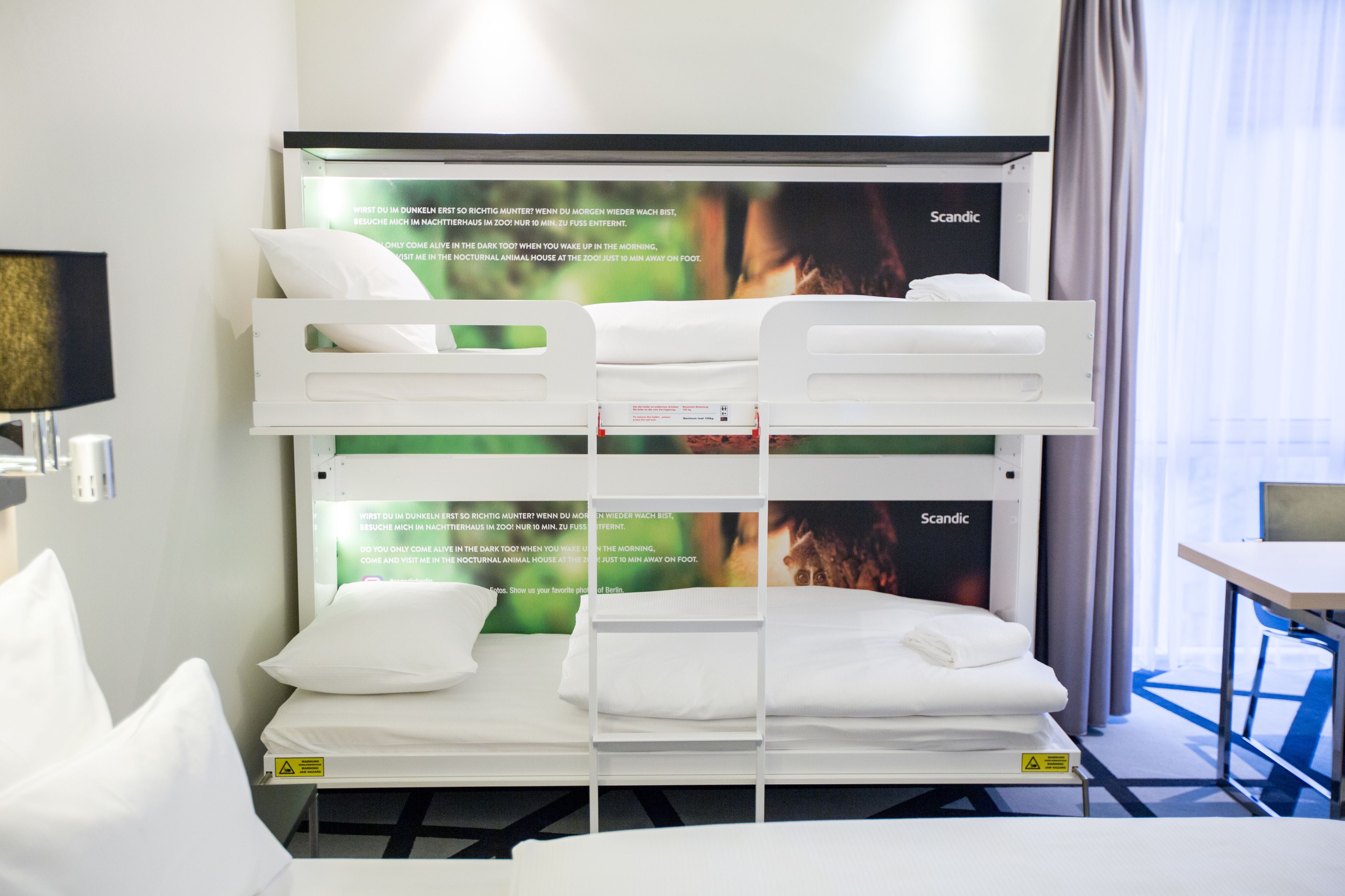 Ein Etagenbett mit wei ßer Bettwäsche und einem Poster im skandinavischen Stil.