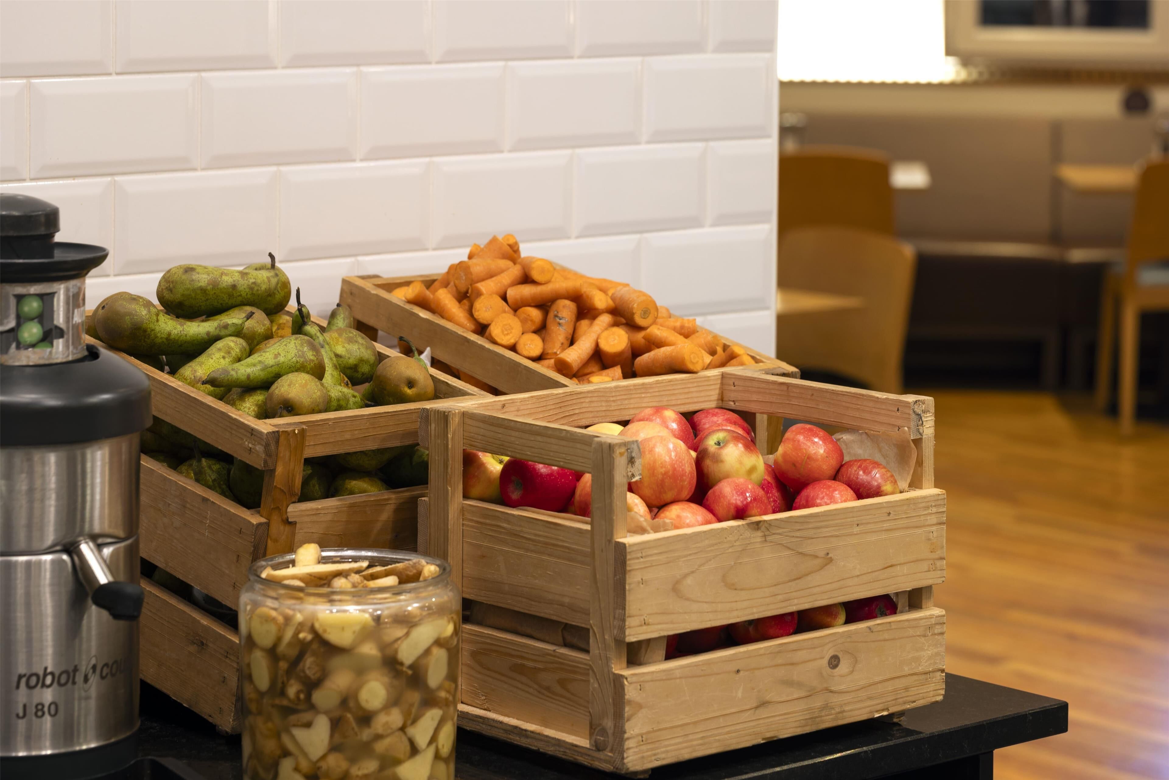 Cajas de madera con peras, manzanas y zanahorias sobre una mesa.