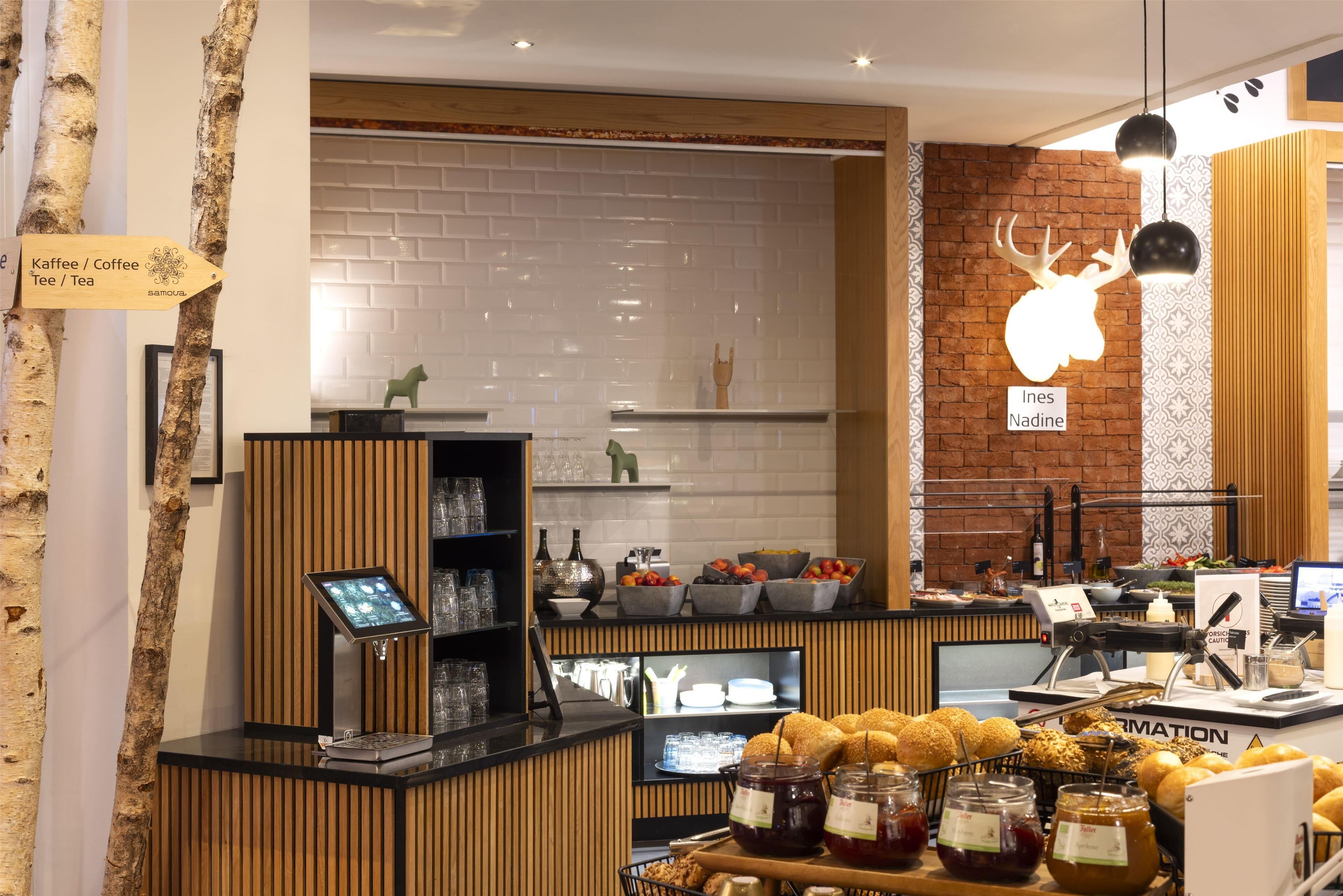 Interior de una cafetería con mostrador de madera, una pizarra con el menú y una pared de ladrillo.