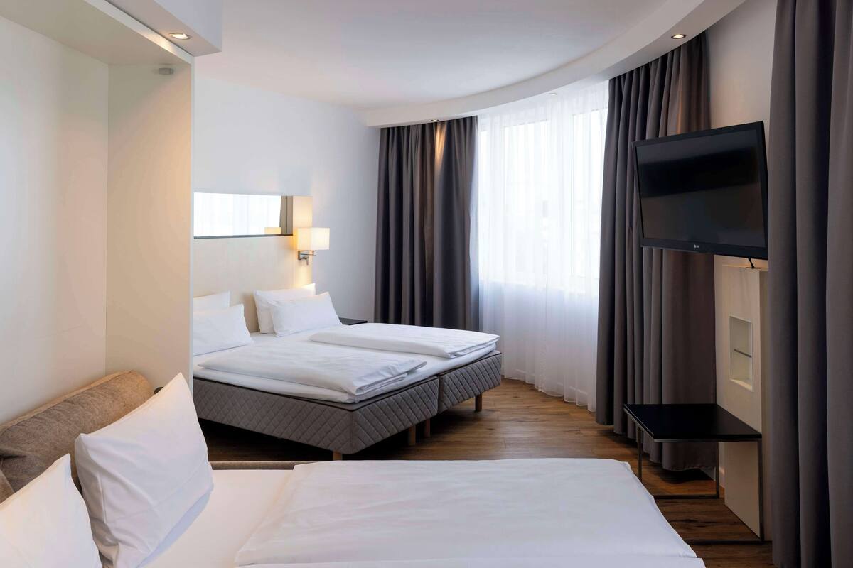 A hotel room with two beds, a TV, and a desk.