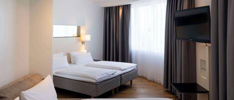 A hotel room with two beds, a TV, and a desk.