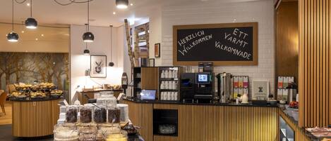 Una cafetería moderna con mostrador de madera, diversas opciones de comida y una pizarra.
