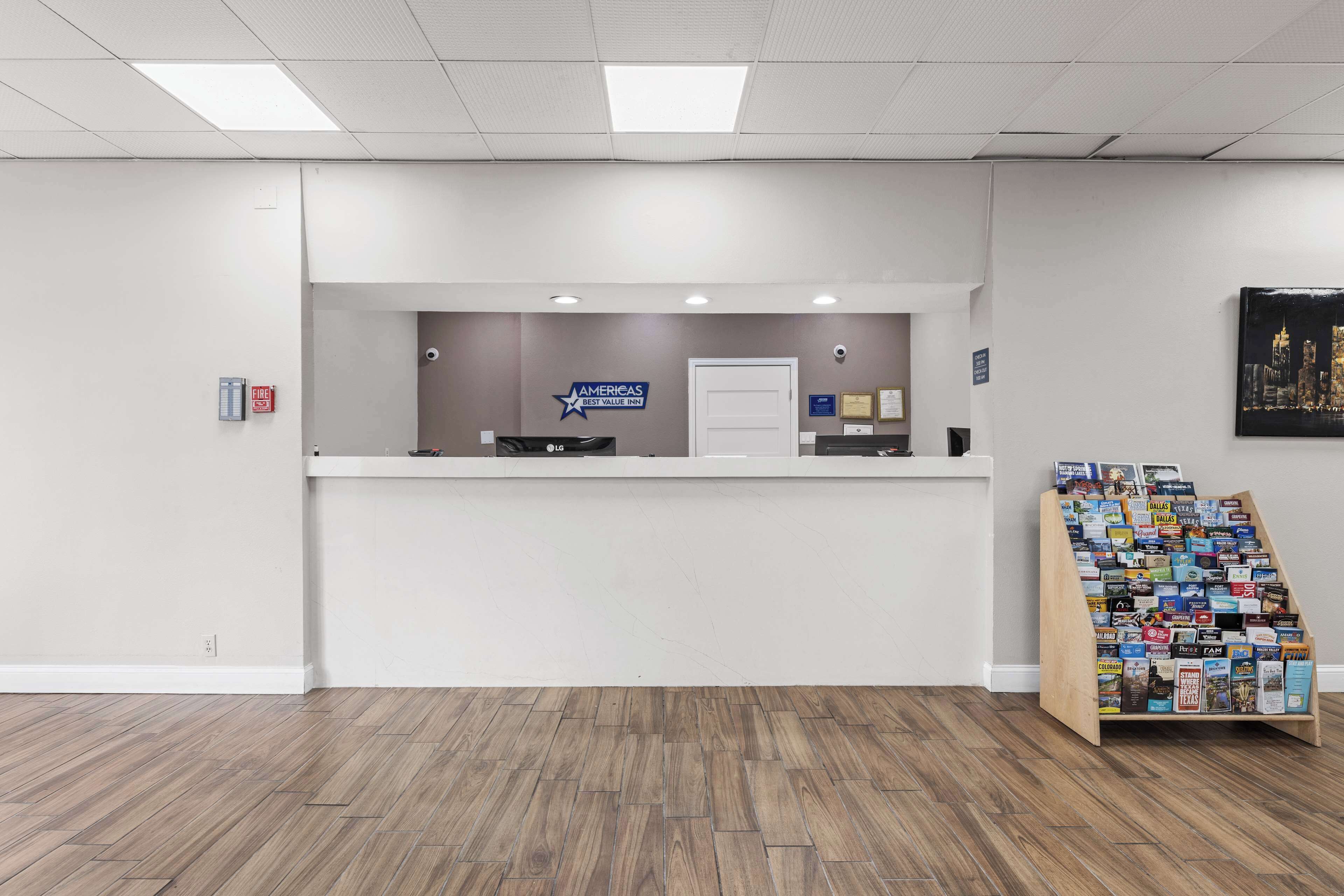 Een receptiegedeelte met een witte balie, een rookmelder en een display met brochures.