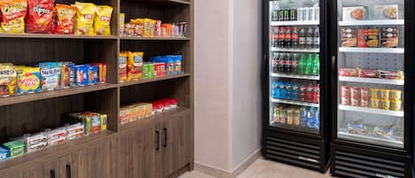 A snack and beverage vending area with multiple shelves stocked with various snacks and drinks.