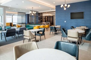 Un restaurante moderno con diversas opciones de asientos, incluyendo cabinas y mesas, una gran pantalla de televisión en la pared y un diseño de interiores contemporáneo.