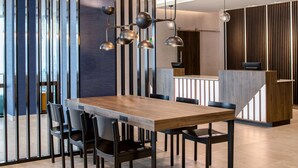 A modern dining area with a wooden table and black chairs, a reception desk, and vertical wooden panels. - La Quinta Inn & Suites by Wyndham Spokane Downtown (Spokane)