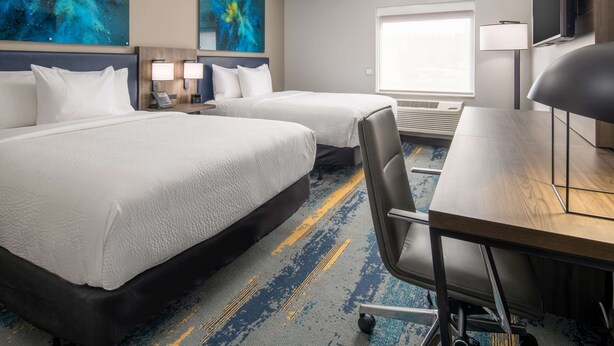 A hotel room with two beds, a desk, a chair, a TV, and artwork on the walls. - La Quinta Inn & Suites by Wyndham Spokane Downtown (Spokane)