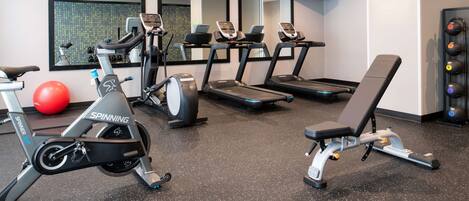 Ett gym med motionscyklar, löpband, en bänk och en röd träningsboll.