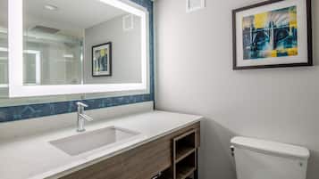 A modern bathroom with a large mirror, a sink, and a toilet.