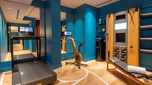 A fitness room with a treadmill, stationary bike, and a massage table. - Urban Hive Milano (Milan)