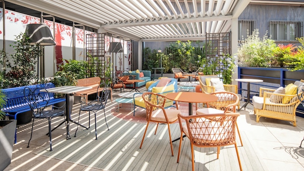 An outdoor patio area with various seating options, including chairs and sofas, and a pergola providing shade. - Urban Hive Milano (Milan)