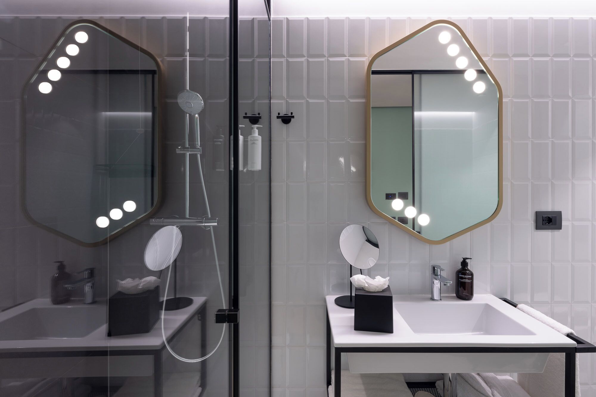 A bathroom with a glass-enclosed shower, two sinks with mirrors, and a towel rack.