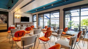A conference room with rows of chairs, large windows, and a flat-screen TV on the wall. - Urban Hive Milano (Milan)
