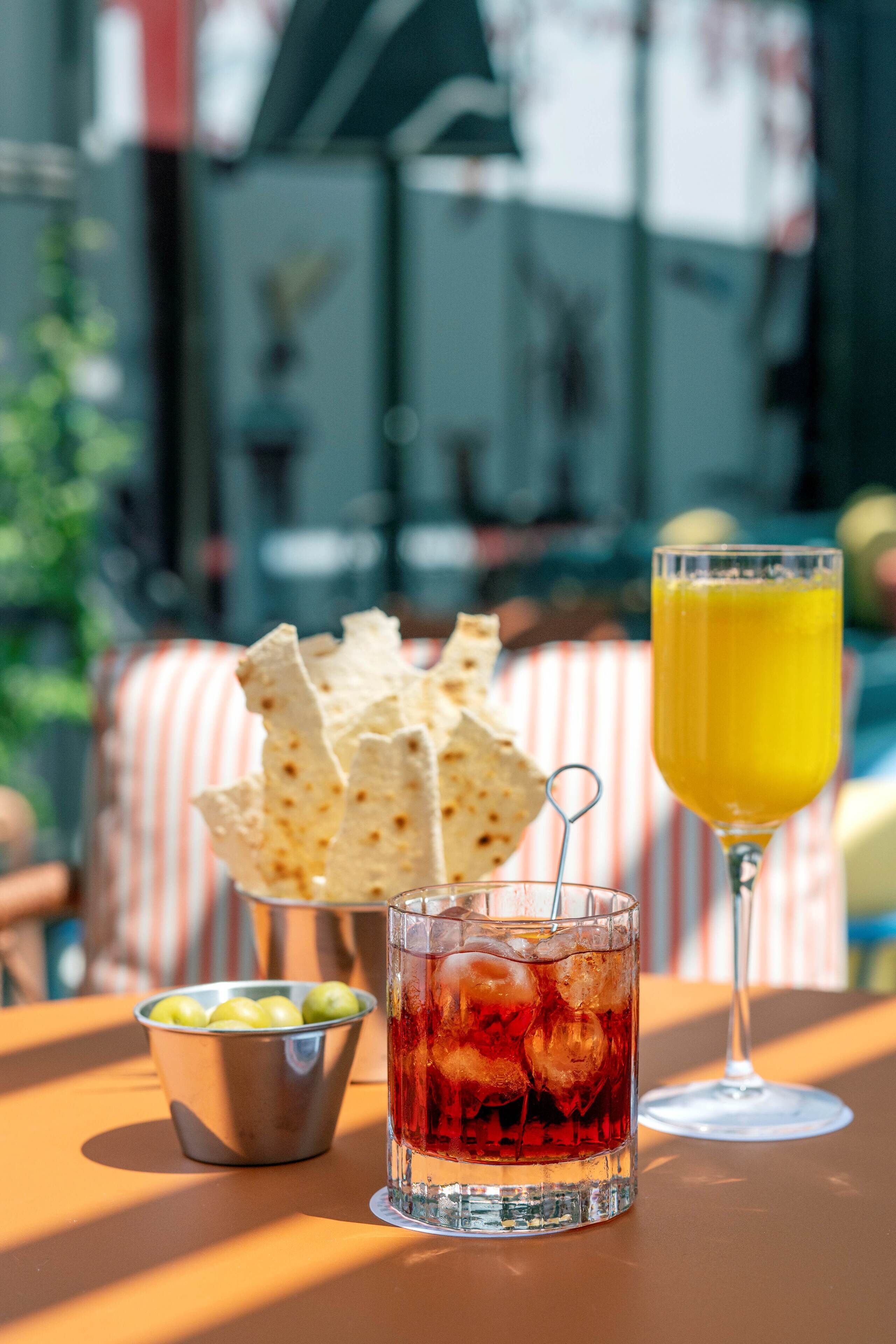 A table with a drink, a bowl of chips, and a glass of juice.