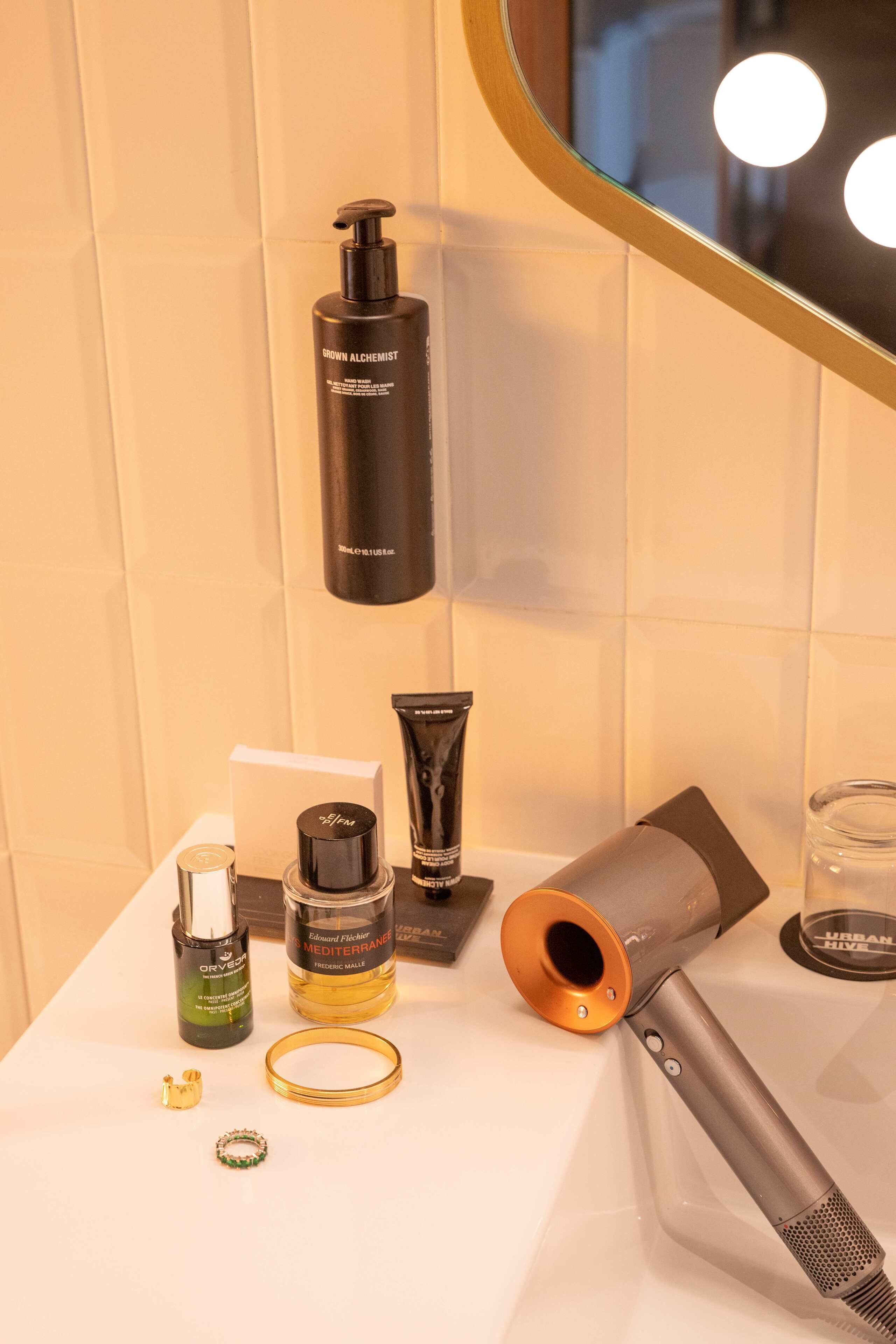 Un meuble-lavabo de salle de bain avec des articles de toilette, un sèche-cheveux et un miroir.