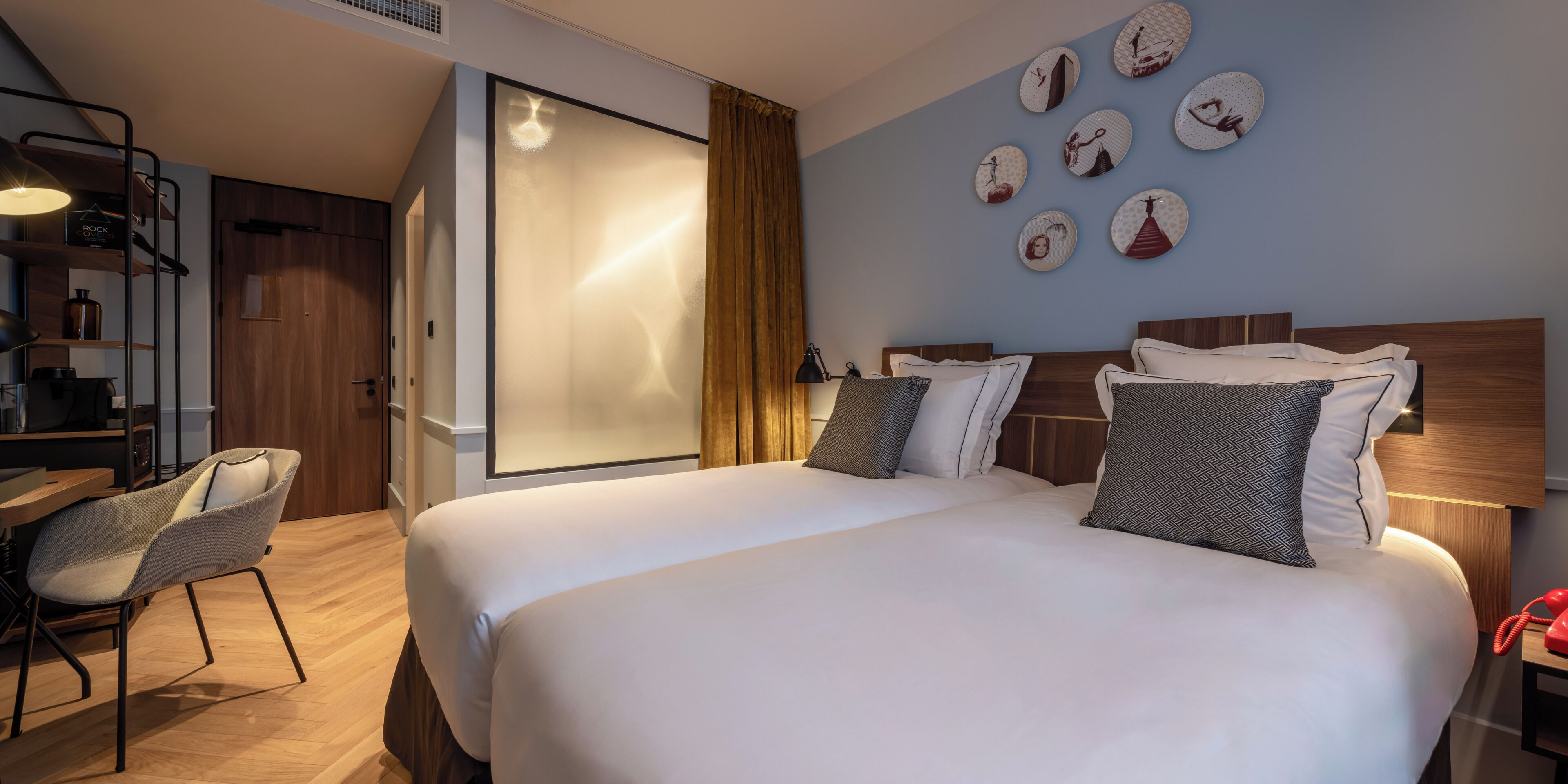 Una camera d'albergo con un letto grande, una scrivania con una sedia, un armadio e una parete decorata con piatti.
