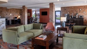 A lobby with a brick wall, a reception desk, a sofa, and a coffee table.