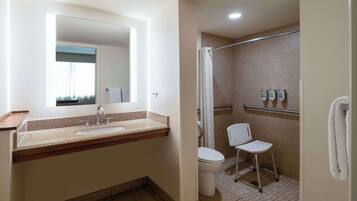 A bathroom with a sink, mirror, shower, and toilet.