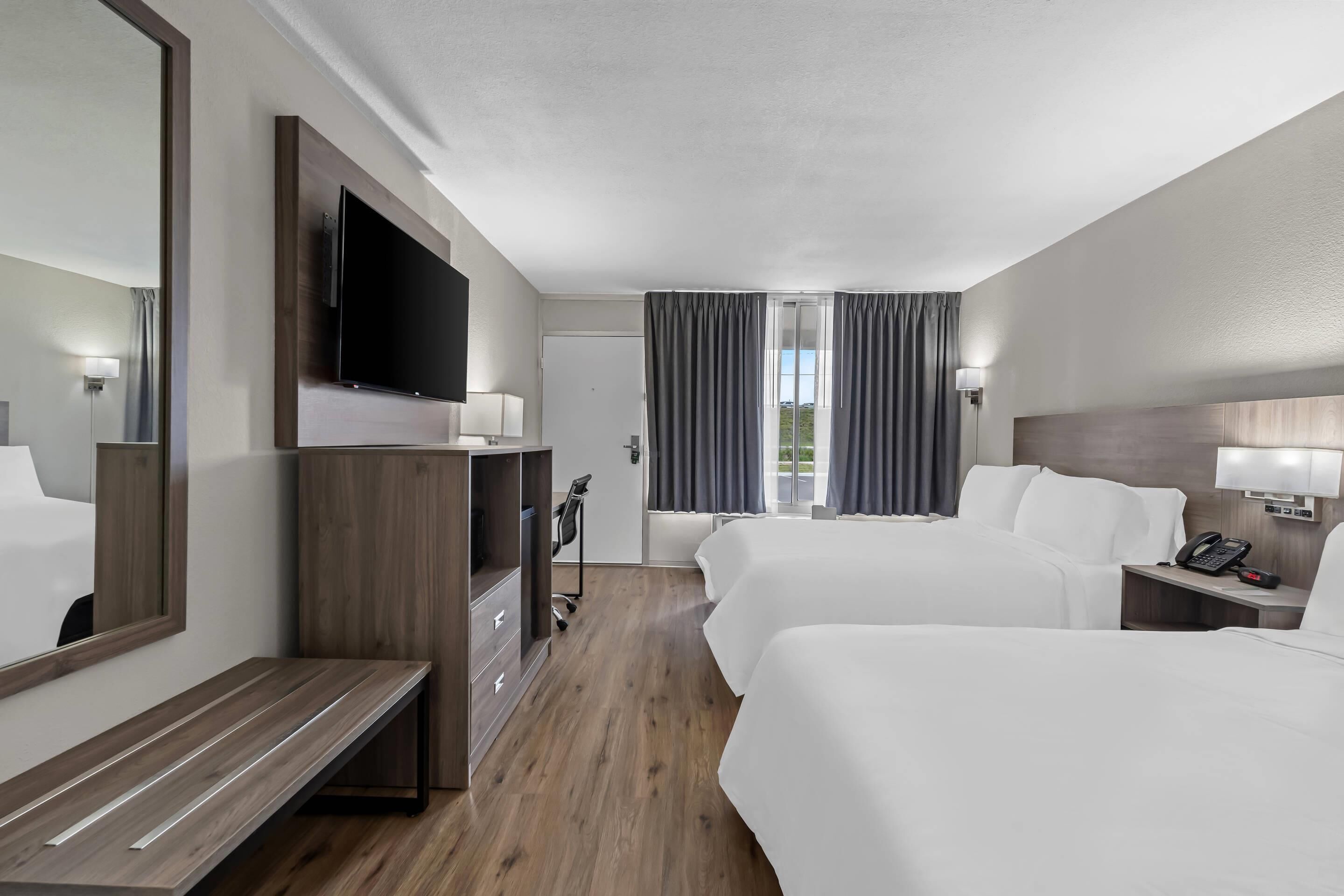 A hotel room with two beds, a TV, a desk, and a wardrobe.