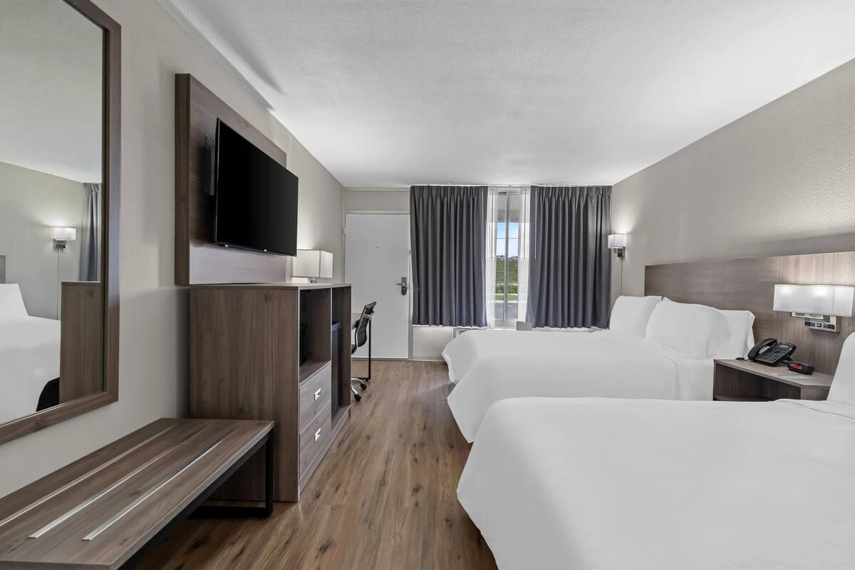 A hotel room with two beds, a TV, a desk, and a wardrobe.
