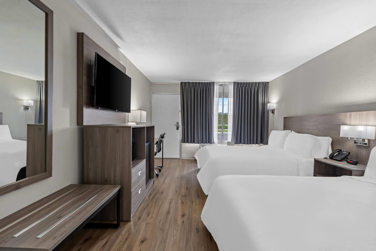 A hotel room with two beds, a TV, a desk, and a wardrobe.