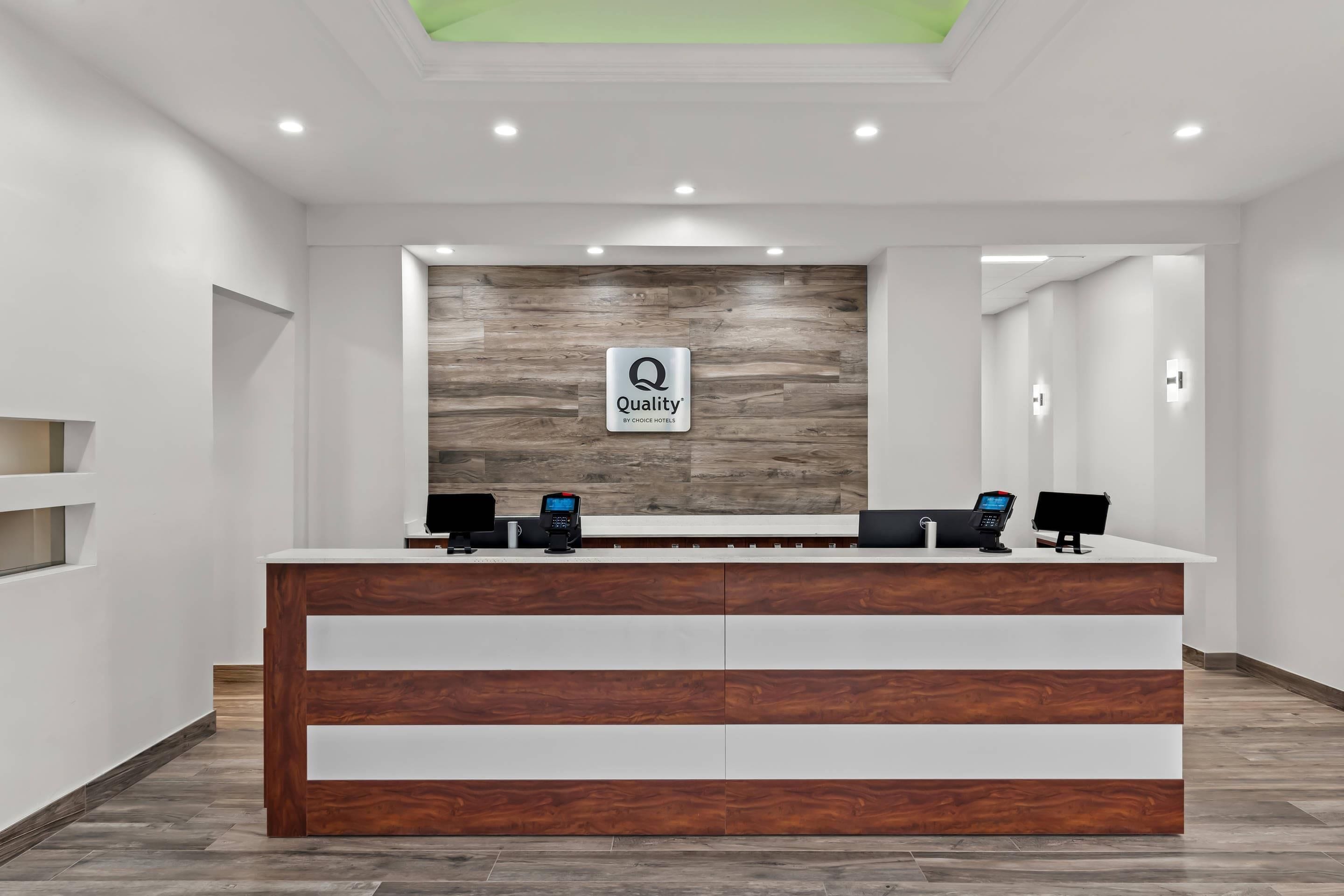 A reception desk with a logo, two computer monitors, and a wooden accent wall.