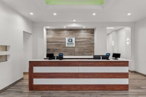 A reception desk with a 'Quality' sign, two computer monitors, and a phone. - Quality Inn & Suites Ocala I-75 (Ocala)
