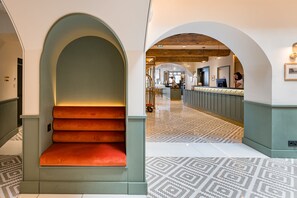 A hotel lobby with a central staircase, a reception desk, and patterned flooring. - Le Phenix Hotel (Lyon)