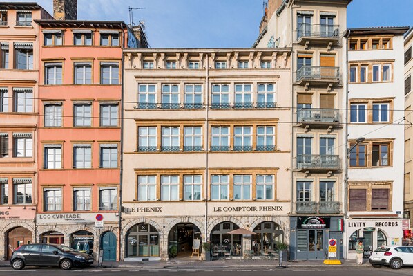 A multi-story building with storefronts including 'Look Vintage' and 'Le Comptoir Phenix'. - Le Phenix Hotel (Lyon)