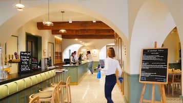 A cafe interior with a counter, wooden chairs, a patterned floor, and a chalkboard menu.