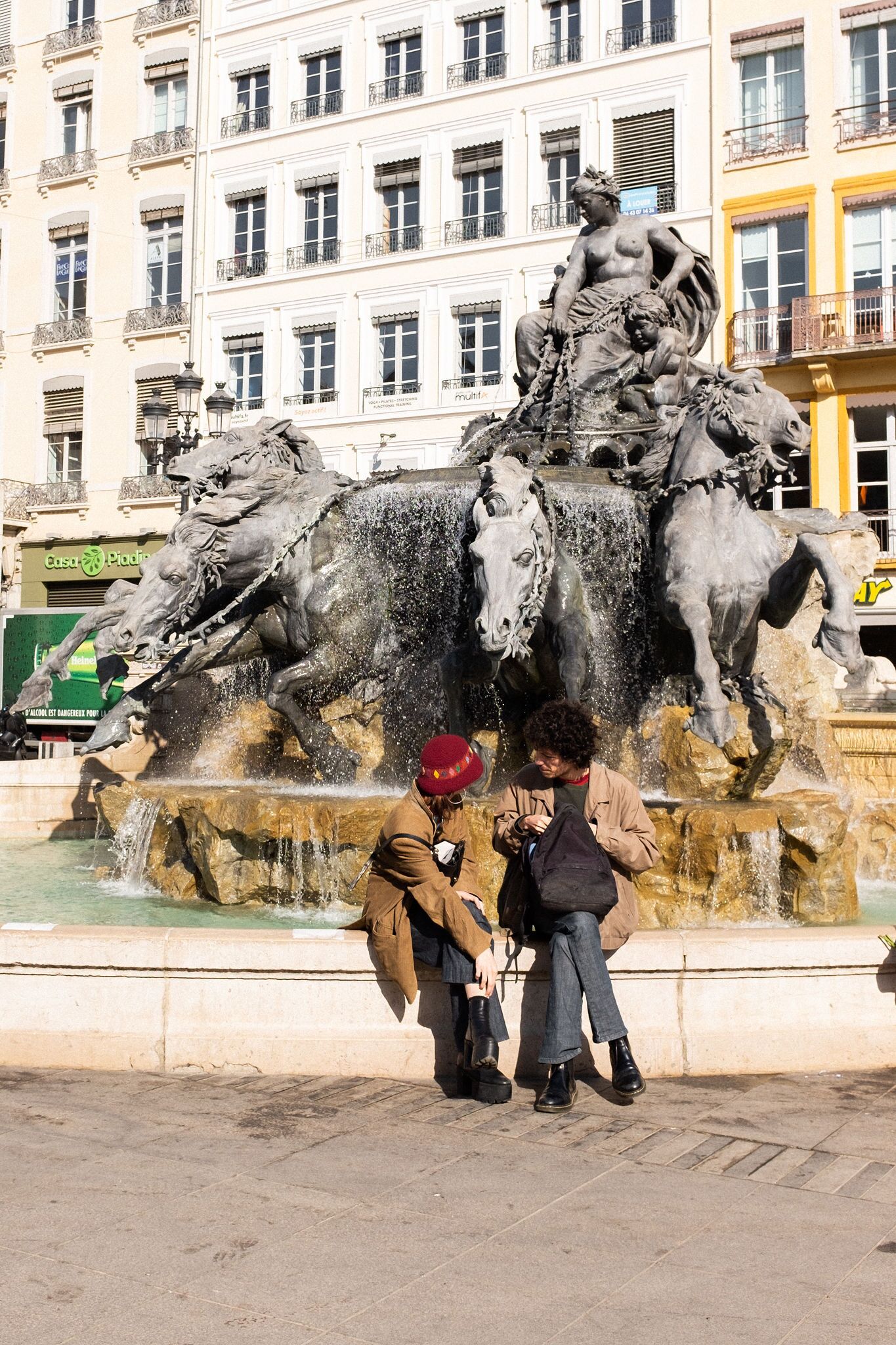 Une fontaine ornée de chevaux et d’une statue représentant un homme et une femme.