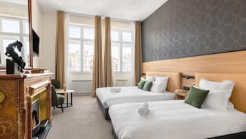 Une chambre d’hôtel avec deux lits, une cheminée, une télévision et de grandes fenêtres avec des rideaux.