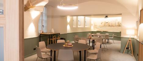 A conference room with round tables and chairs, a stone arch ceiling, and a cityscape view through the windows.