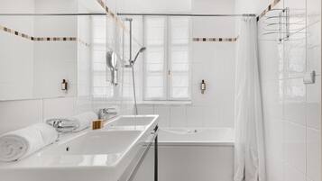 Un baño moderno con una bañera grande, zona de ducha separada y tocador con espejo.