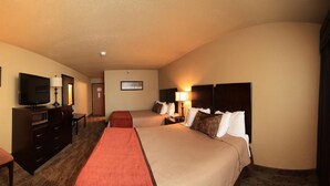 A hotel room with two beds, a TV, a desk, and a lamp.