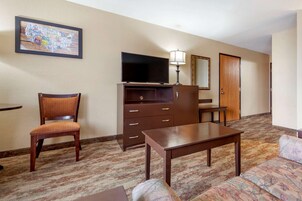 Une chambre d’hôtel équipée d’une télévision, d’un bureau, d’une chaise, d’un canapé, d’une commode et d’un miroir.