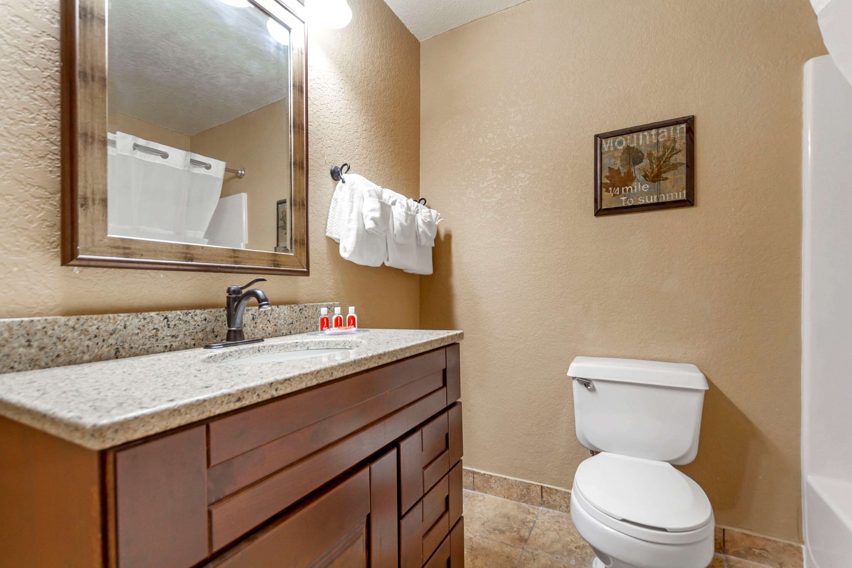 Un baño con lavamanos, espejo, toallero y retrete.