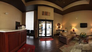 A lobby with a reception desk, seating area, and a large glass door entrance.